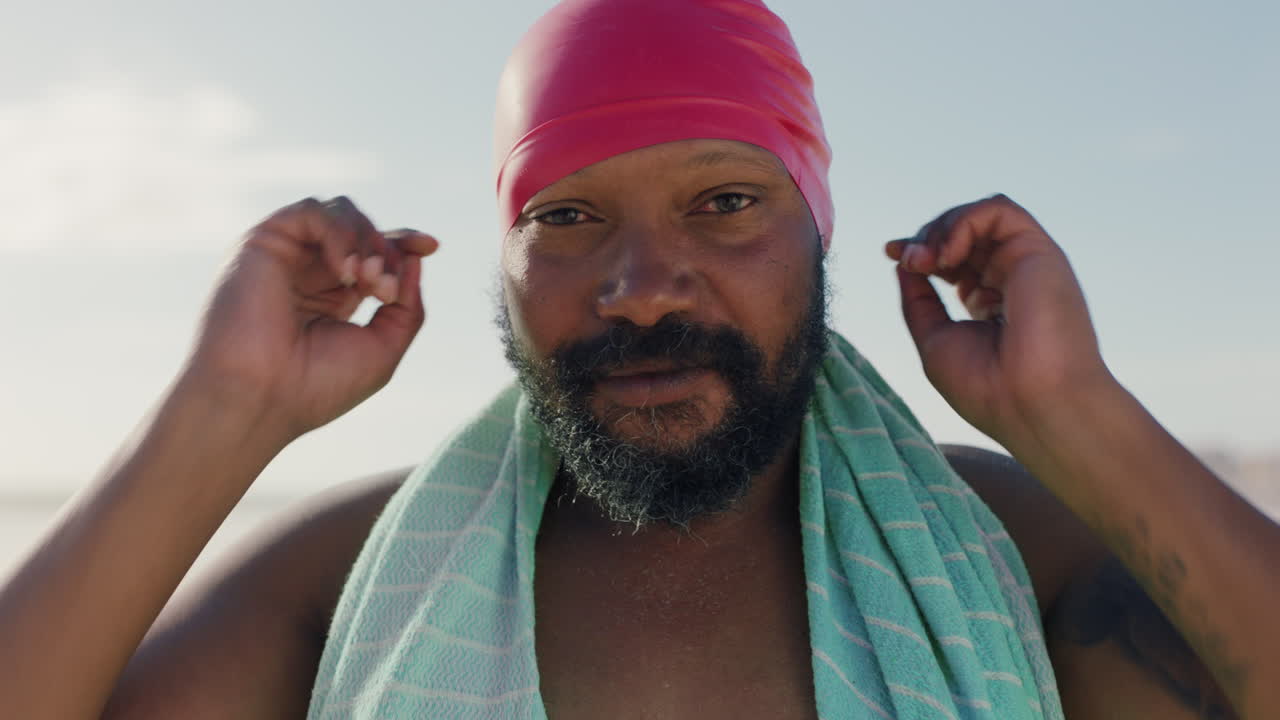 retrato feliz hombre afroamericano con gorra de natación en la playa disfrutando de una hermosa mañana junto al mar preparándose para nadar imágenes de 4k
