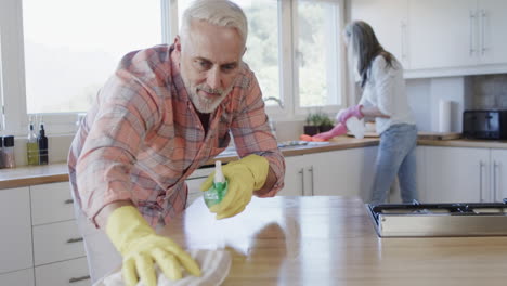 middle aged caucasian couple cleaning kitchen at home, slow motion