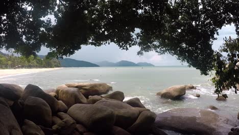 serene tropical beach with rocks and lush trees