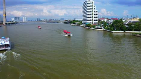 double-decker tourist boat and long boats cruising on the chao phraya river near rama viii bridge in bangkok, thailand