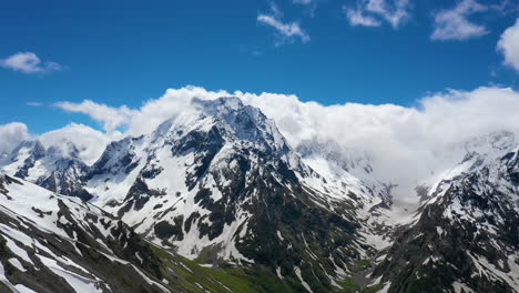 air flight through mountain clouds over beautiful snow-capped peaks of mountains and glaciers.