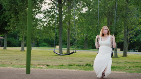 young pregnant woman riding a swing in the park