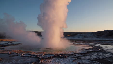 geyser erupting steam in a geothermal landscape at dawn or dusk