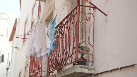 Clothes-on-a-clothesline-hanging-from-a-balcony-window-in-Lisbon,-Portugal