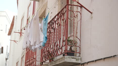 clothes on a clothesline hanging from a balcony window in lisbon, portugal