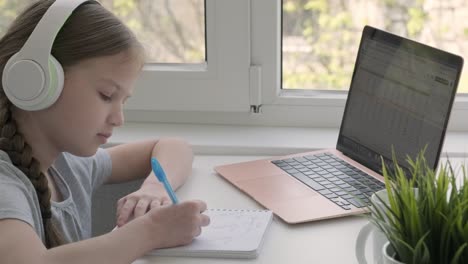 focused school girl wearing wireless headphones studying online at virtual class with teacher tutor
