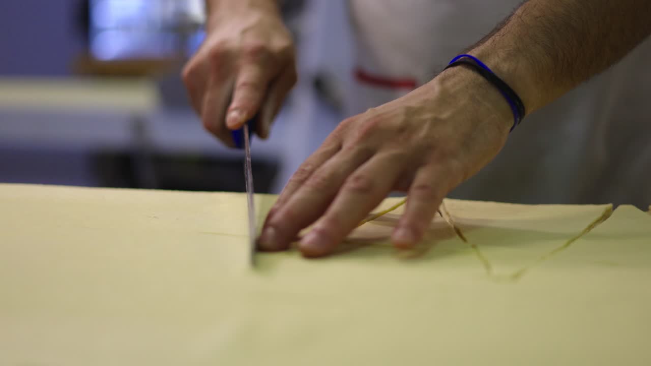 las manos del pastelero cortando la masa en formas para la preparación de croissants
