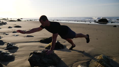 Un-Hombre-Fuerte-Balanceándose-En-Una-Pose-De-Yoga-Durante-Un-Entrenamiento-Meditativo-Al-Amanecer-En-Una-Playa-En-Santa-Barbara,-California-A-Cámara-Lenta