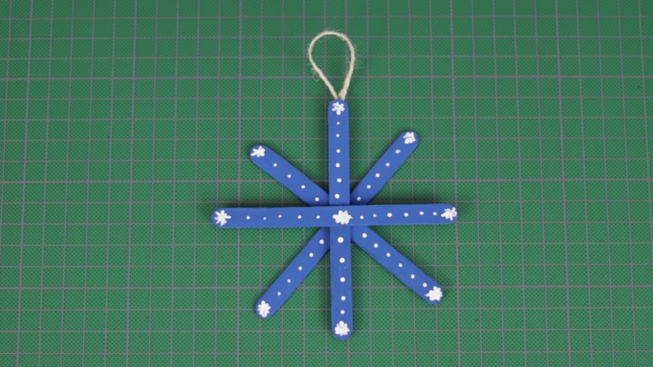 copo de nieve azul hecho de palitos de paleta en una alfombra de corte