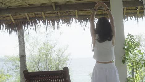 Brunette-woman-on-her-back-stretching-on-exotic-hotel-terrace-with-sea-views