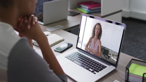 African-american-businesswoman-sitting-at-desk-using-laptop-having-video-call-with-female-colleague