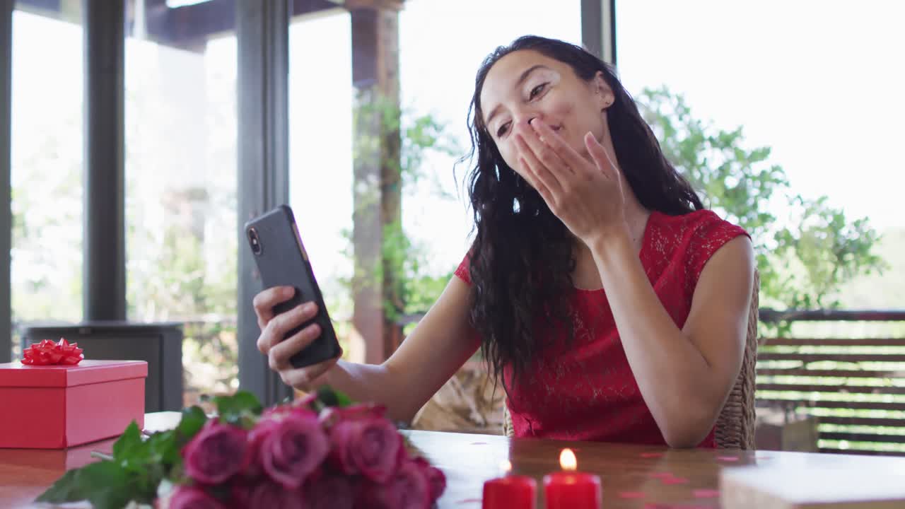Happy biracial woman making valentine's day video call on tablet, sending kisses