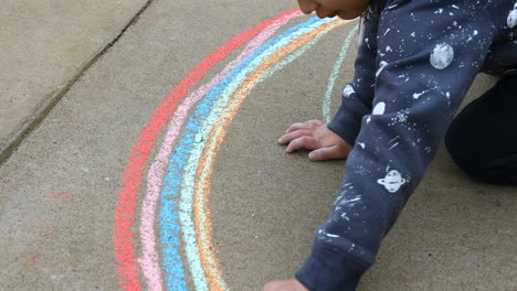 Young-boy-age-4-years-old,-drawing-on-sidewalk-with-chalk