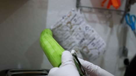 a cucumber is peeled with a potato peeler