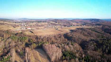 Rural-agriculture-fields-and-forestery-around-Polanczyk-village-in-Poland-with-houses,-hotels-and-apartments-built-on-sloppy-hills---aerial-high-up-flyover