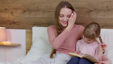 Junge-Mutter-Und-Kind-Tochter-Liegen-Zu-Hause-Im-Bett-Und-Lesen-Gutenachtgeschichten,-Märchen