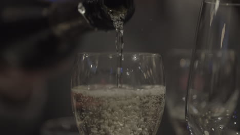 slowmotion-schuss von champagner, der in ein glas gegossen wird, während einige blasen nach oben kommen