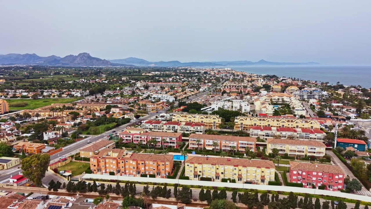 Vista di una città costiera con edifici, strade e montagne sullo sfondo durante il giorno.
