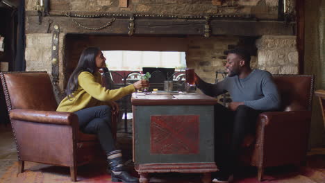 Couple-Making-Toast-As-They-Meet-For-Lunchtime-Drinks-In-Traditional-English-Pub