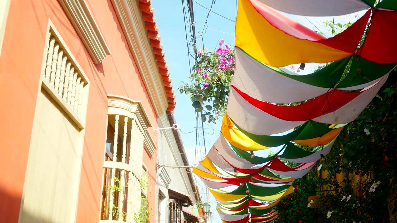 Striscioni in Tessuto Colorati Appesi in Alto Sopra una Strada Storica con Edifici Coloniali a Cartagena, Colombia. Inquadratura dal basso, carrellata in avanti