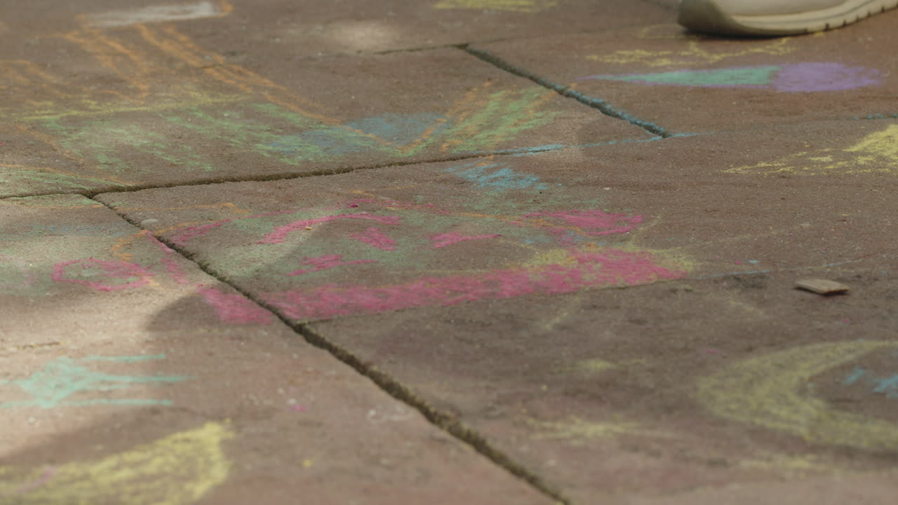 Close up shot of grandma drawing with a pink chalk onto terrace stones