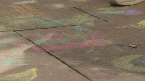 close up shot of grandma drawing with a pink chalk onto terrace stones