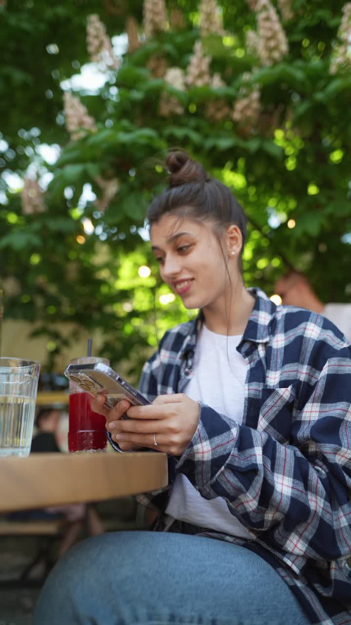 joven usando un teléfono inteligente en un café al aire libre
