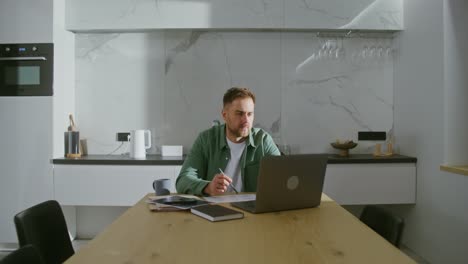 hombre trabajando desde casa en una cocina moderna