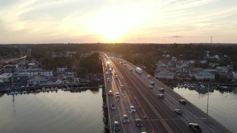 drone shot tracking forward over interstate on bridge at golden hour, with moderate heavy traffic