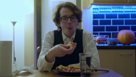 un joven disfrutando de una pizza y una bebida