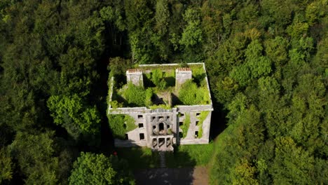 Slow Aerial Pull Back of Moore Hall Ruins Hidden in a Forest with the Sun Shining