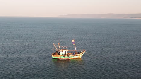 aerial view around a traditional fishing boat in calm sea, golden hour in india