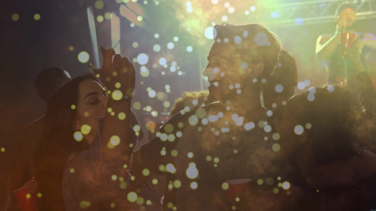 Mand i midten reagerer med venner på en sanger, der løfter mikrofonen til koncert, med bokeh svævende over ansigterne.