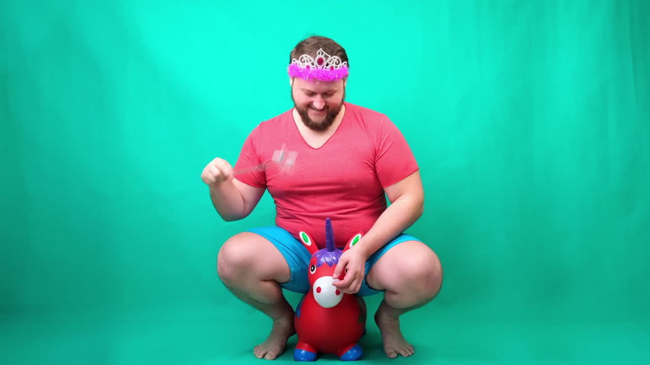 video gracioso, un hombre raro en un pequeño caballo rosa con una varita mágica en un fondo verde