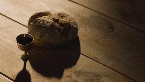 concepto religioso filmado con pan de cáliz y vino en una mesa de madera con un charco de luz 4