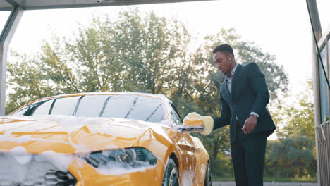 hombre lavando un coche amarillo