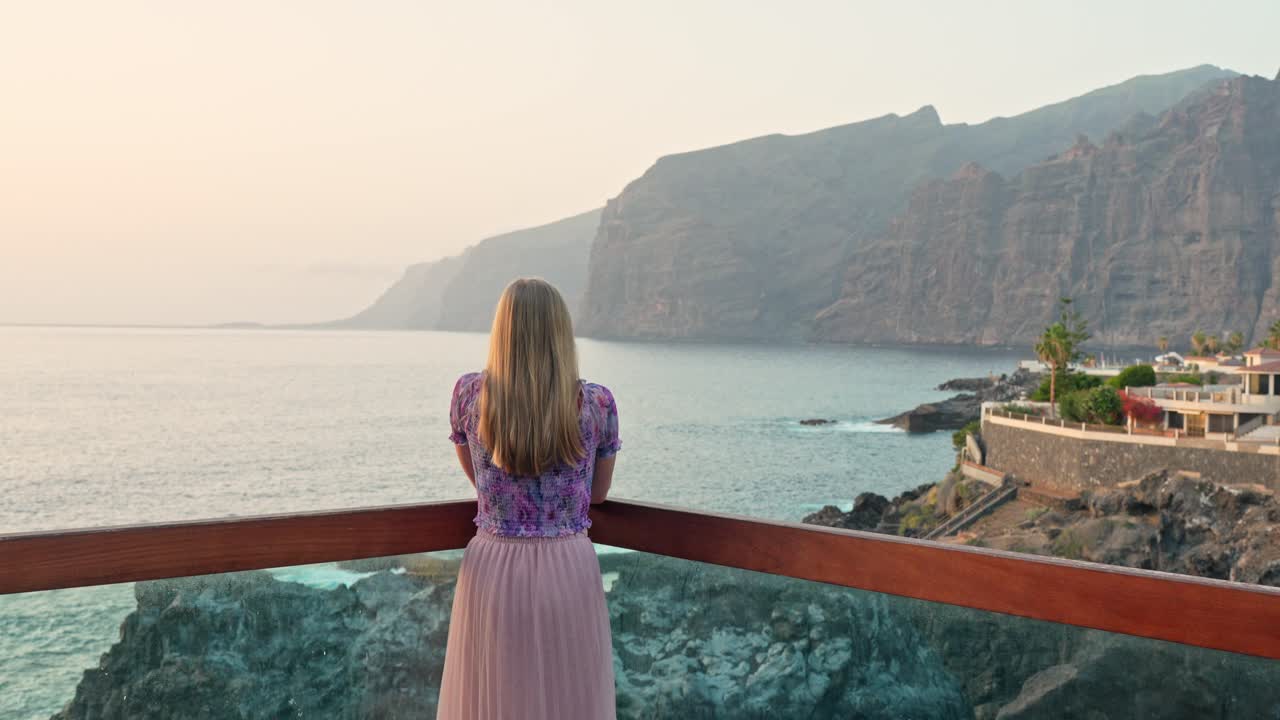 Woman walks to overlook above Los Gigantes Tenerife to take in beautiful ocean vista