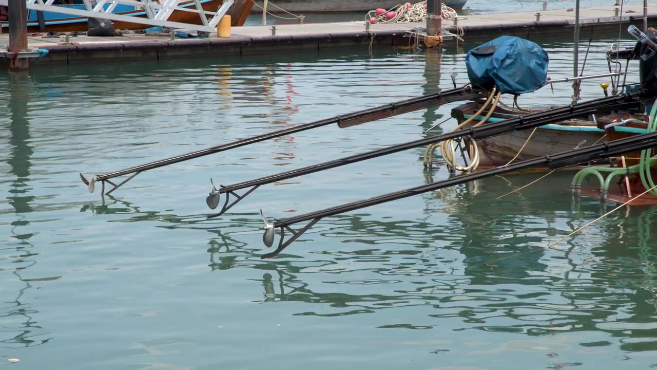 Statische Weitwinkelaufnahme von traditionellen thailändischen Longtail-Bootmotoren und Propellern an einem Marinasteg