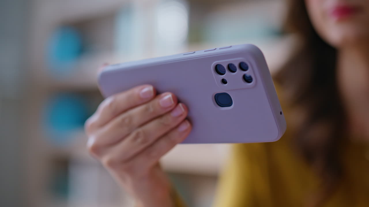 Hand holding horizontal cellphone in apartment closeup. Unrecognizable woman