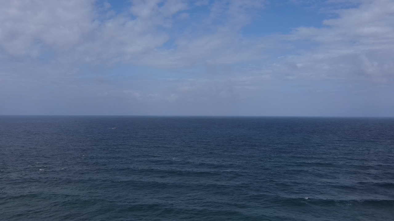 Højvinkel droneoptagelse, der viser den fjerntliggende Morant Point-halvø. Det historiske fyrtårn fra det 19. århundrede fungerer som en ensom vagtpost på den klippefyldte jamaicanske kyst.