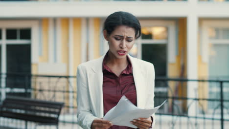 Sad-businesswoman-feeling-upset-with-project-data-outdoors,-Lady-reading-papers