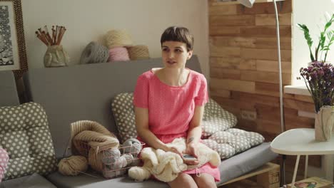 Creative-woman-sitting-on-couch-talking-with-friend-on-background-knitting-yarn