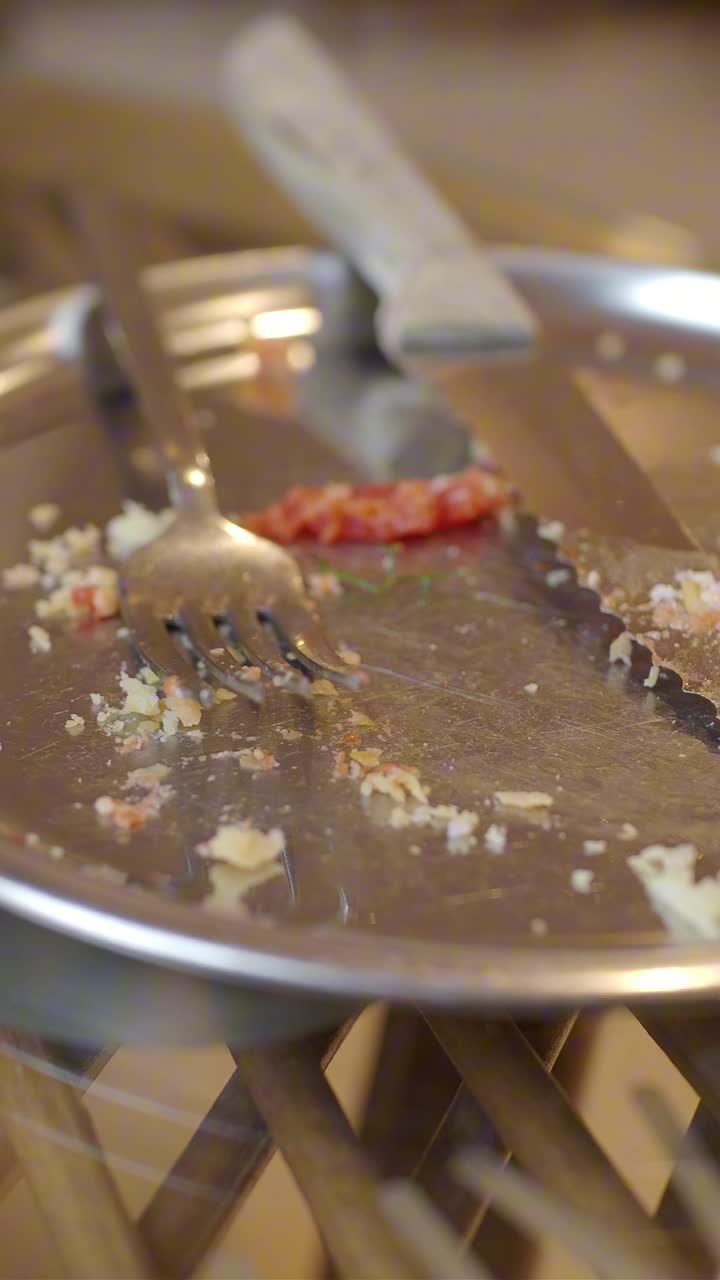 Empty Dirty Plate with Food Crumbs and Cutlery After a Meal