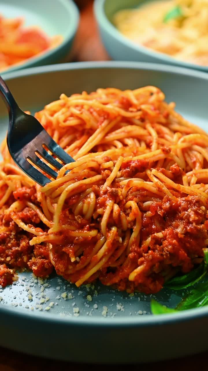 Spaghetti con sugo di carne rosso e parmigiano grattugiato. Primo piano di spaghetti alla bolognese con forchetta, che mostra la consistenza della carne macinata e del formaggio su un piatto di ceramica blu.