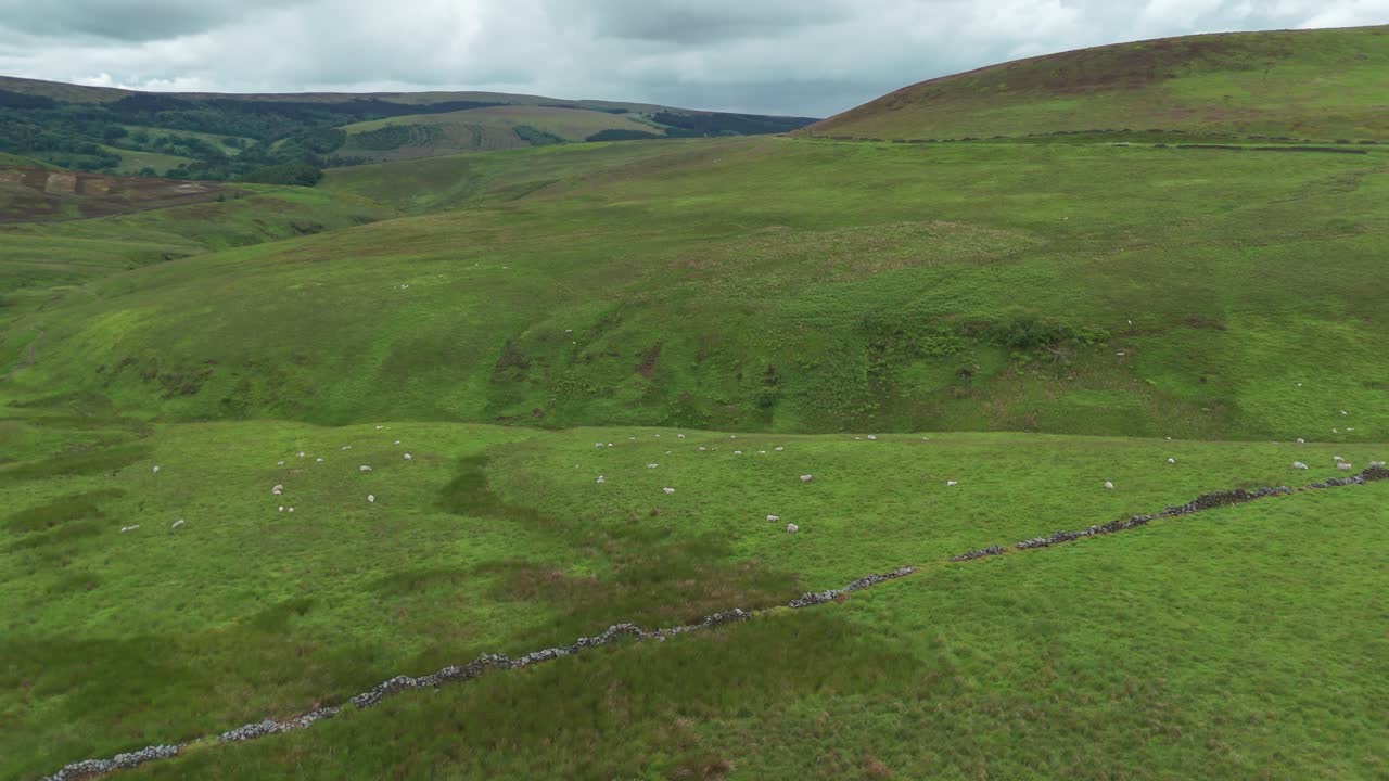 Rotating aerial view of empty green fields of Peak District National Park during cloudy day in England