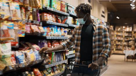 cliente masculino tomando productos del estante en el supermercado, puesto en el carrito