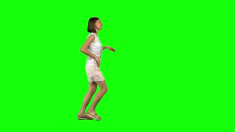 young woman with brown hair and smooth haircut is running with smile on green screen. chroma key, 4k shot. profile view