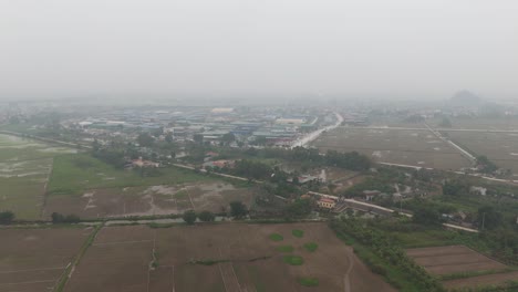 Toma-Aérea-De-Drones-De-Campos-De-Hierba-Con-Casas-Pequeñas-En-Vietnam