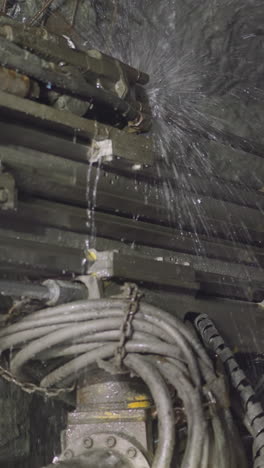 robot drill makes hole for setting explosives in hard rocks spraying cold water. heavy machinery equipment with coolant operates in ore mine closeup