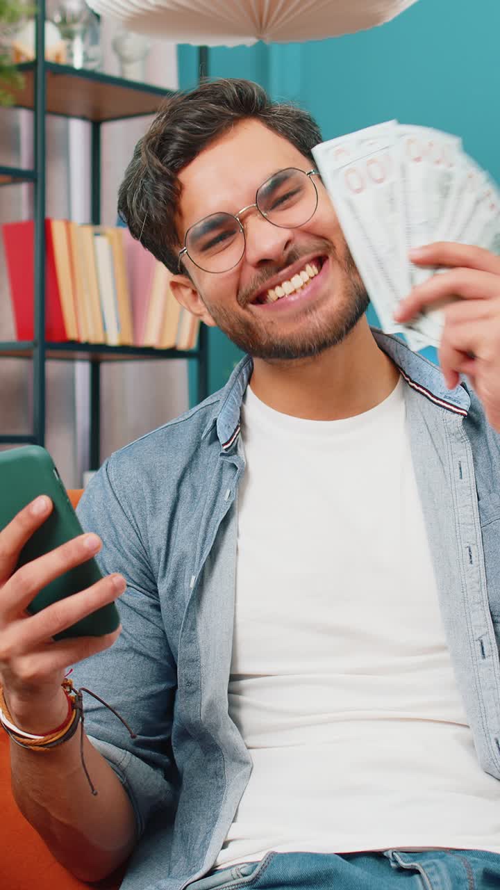 Hombre rico y feliz de India contando dinero en efectivo en el teléfono inteligente aplicación calculadora calcular ingresos ganancias